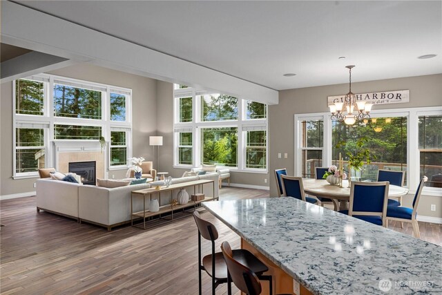 dining area with baseboards, wood finished floors, a notable chandelier, and a fireplace