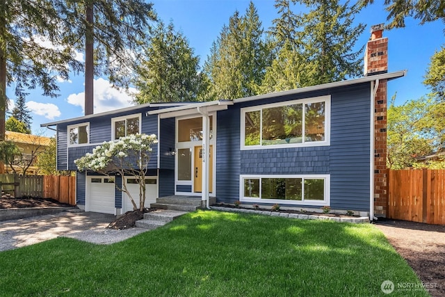 bi-level home featuring concrete driveway, a chimney, a front lawn, and fence