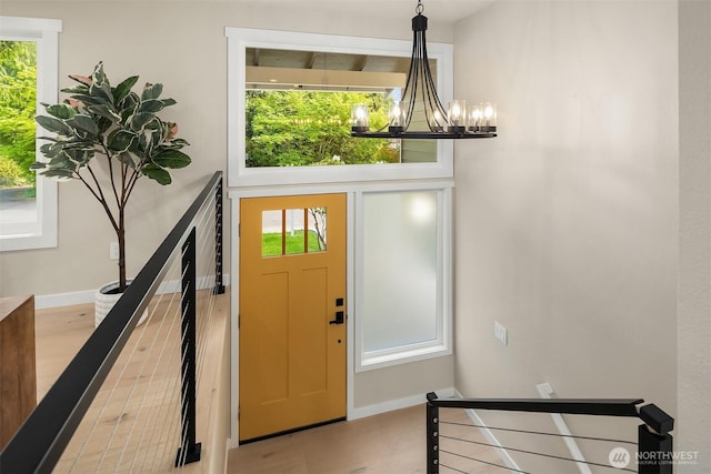 foyer featuring a notable chandelier, baseboards, and wood finished floors