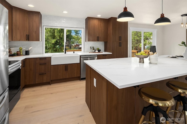 kitchen featuring backsplash, stainless steel appliances, a sink, and plenty of natural light