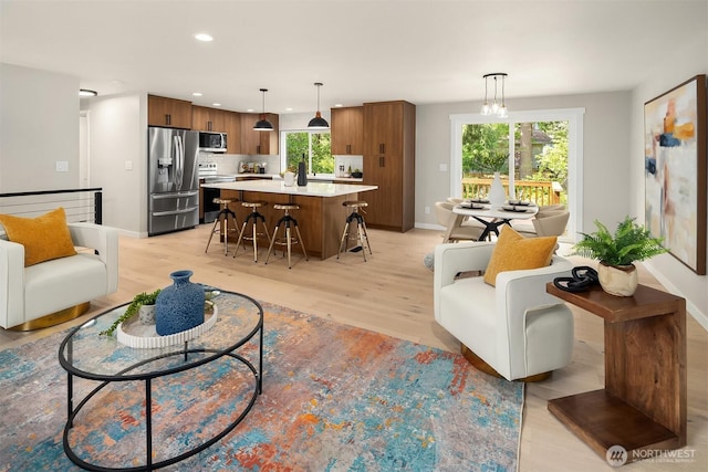 living room featuring baseboards, light wood-style flooring, and recessed lighting