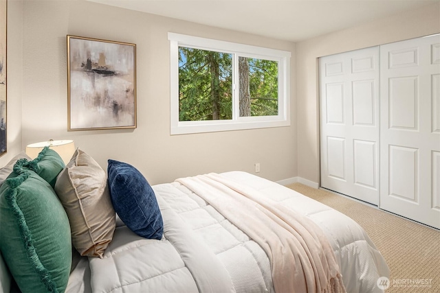 carpeted bedroom with a closet and baseboards