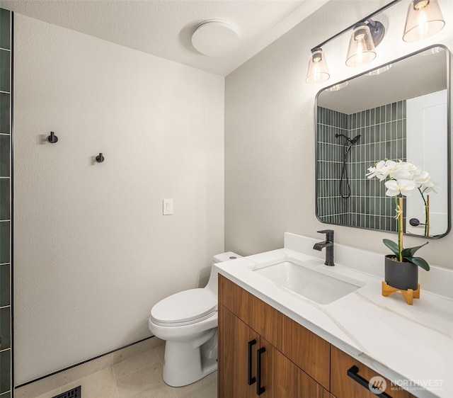 full bath with vanity, toilet, and a tile shower