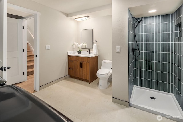 bathroom with toilet, tiled shower, and vanity