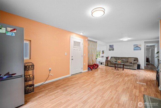 living area featuring light wood-style floors and baseboards