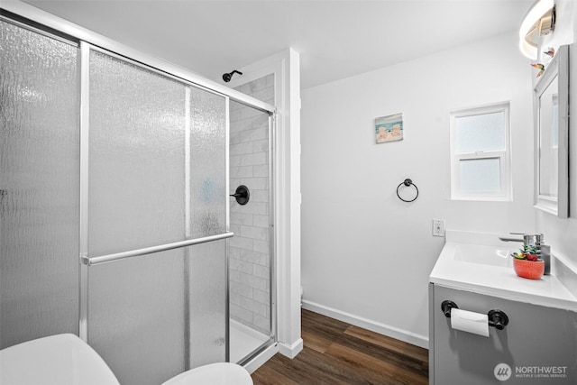 bathroom with a stall shower, toilet, and wood finished floors