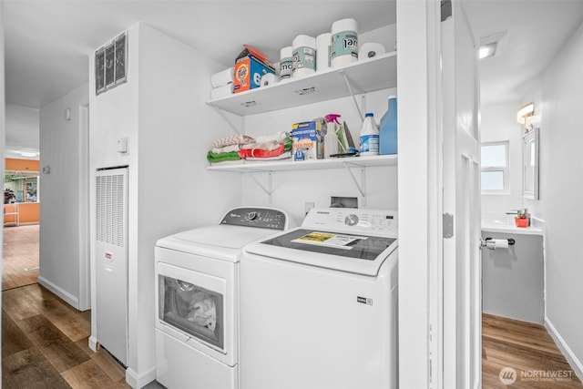 washroom with laundry area, dark wood-style flooring, independent washer and dryer, visible vents, and a heating unit