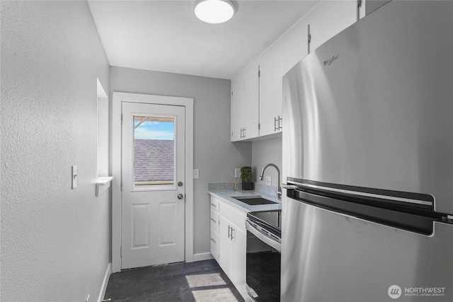 10704 5th Ave S, Tacoma, WA 98444 - kitchen featuring freestanding refrigerator, baseboards, electric stove, white cabinets, and a sink