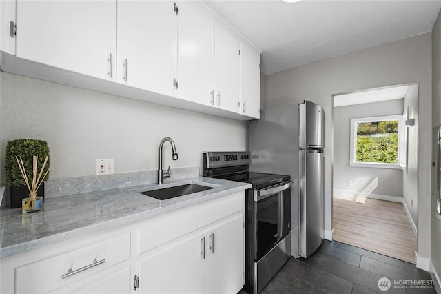 10704 5th Ave S, Tacoma, WA 98444 - kitchen with baseboards, white cabinets, light stone counters, a sink, and stainless steel appliances