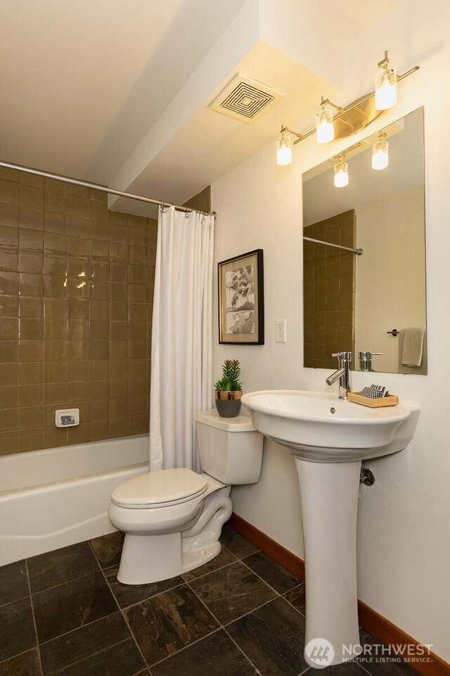 bathroom with toilet, baseboards, visible vents, and shower / tub combo