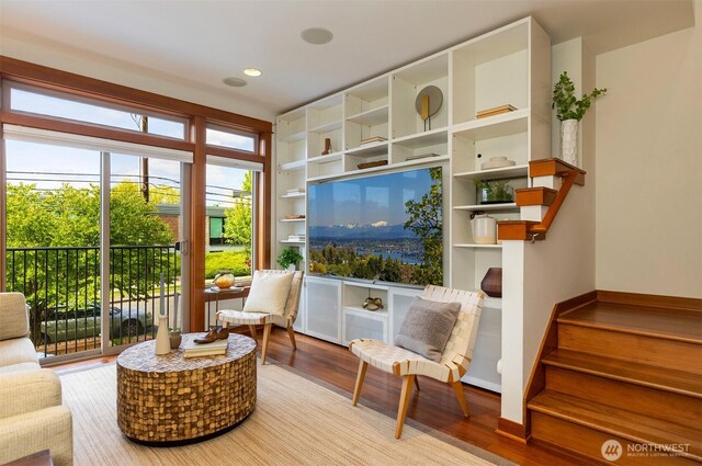 sitting room with stairs, built in shelves, and wood finished floors