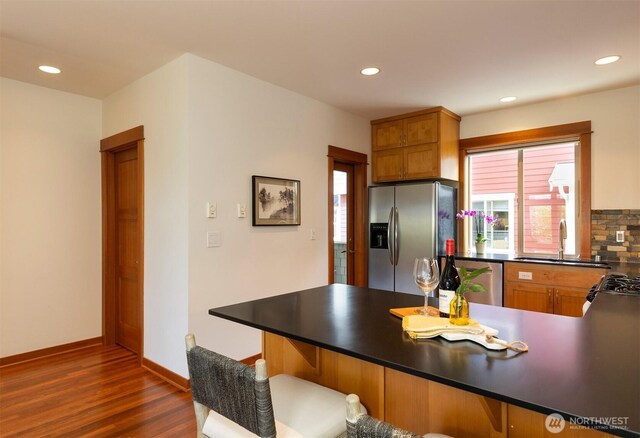 kitchen featuring dark wood-style flooring, dark countertops, a sink, stainless steel appliances, and recessed lighting