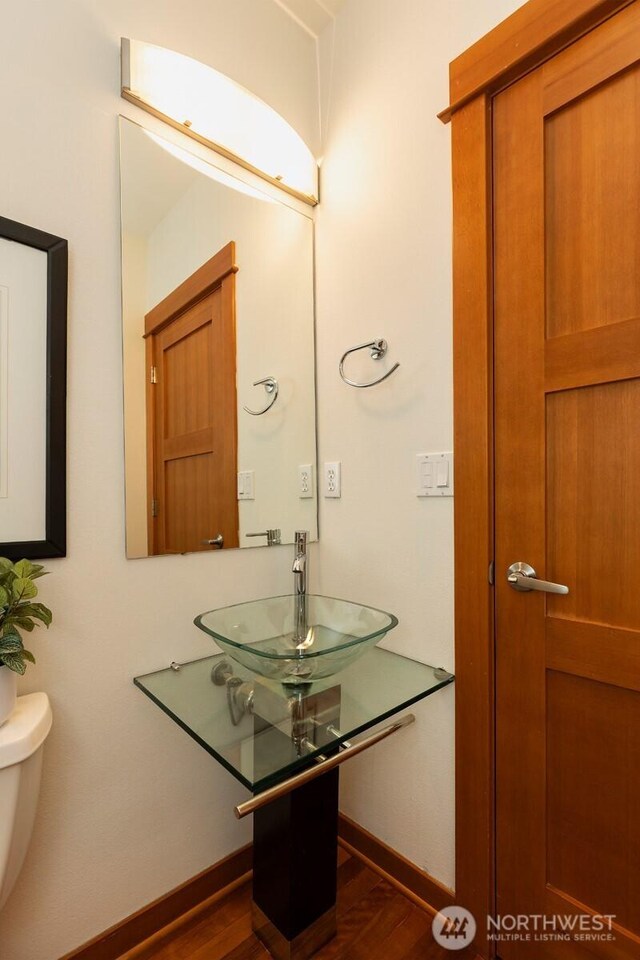 bathroom with baseboards, a sink, wood finished floors, and toilet