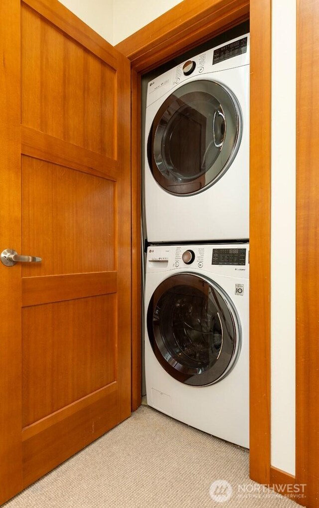 washroom featuring stacked washer and clothes dryer, laundry area, and light colored carpet