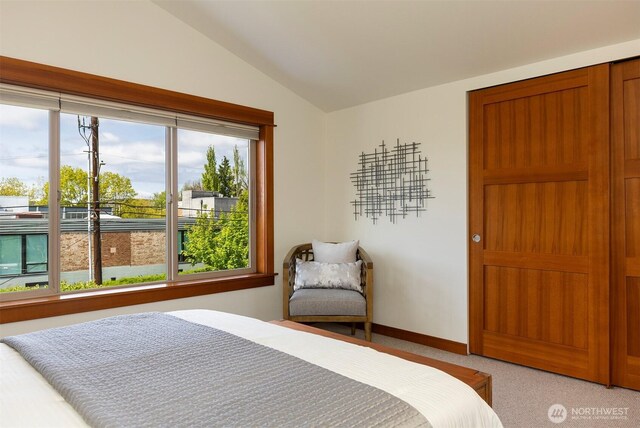bedroom featuring baseboards, lofted ceiling, and light carpet