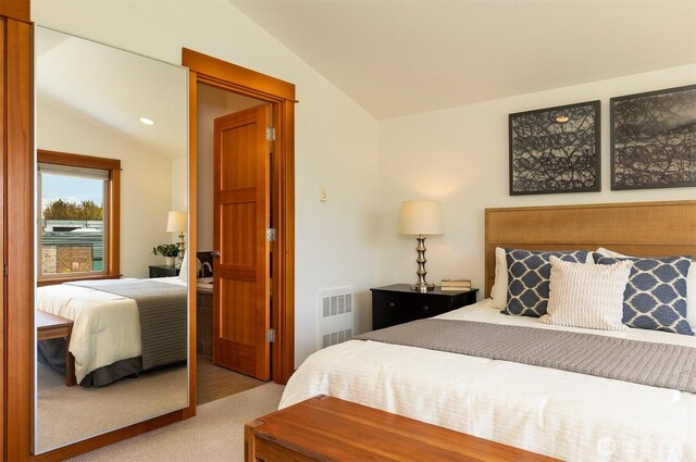 bedroom with visible vents, vaulted ceiling, and light colored carpet