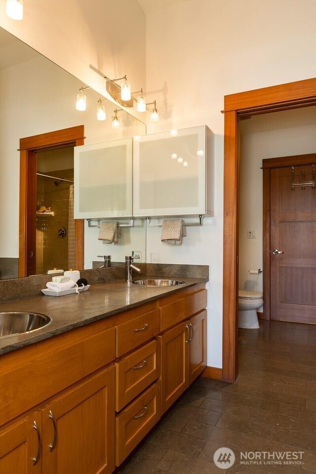 bathroom with double vanity, toilet, a sink, and a shower