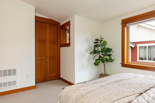 carpeted bedroom featuring baseboards, lofted ceiling, and radiator