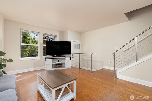 living room featuring stairs, baseboards, and wood finished floors