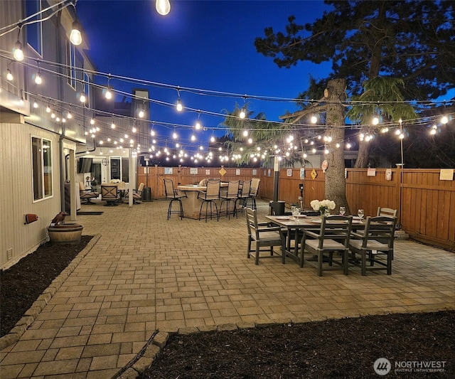 patio at night with a fenced backyard and outdoor dining area