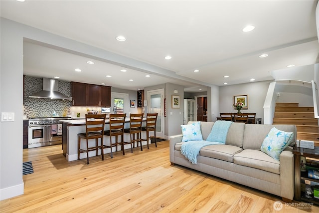 living area with light wood-style floors, recessed lighting, baseboards, and stairway