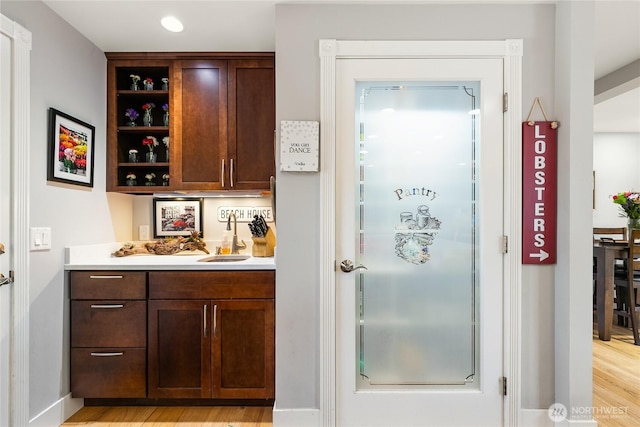 bar featuring light wood-style floors, a sink, and wet bar