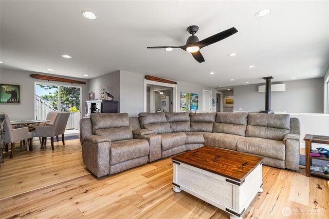 living room featuring a wood stove, recessed lighting, ceiling fan, and light wood finished floors