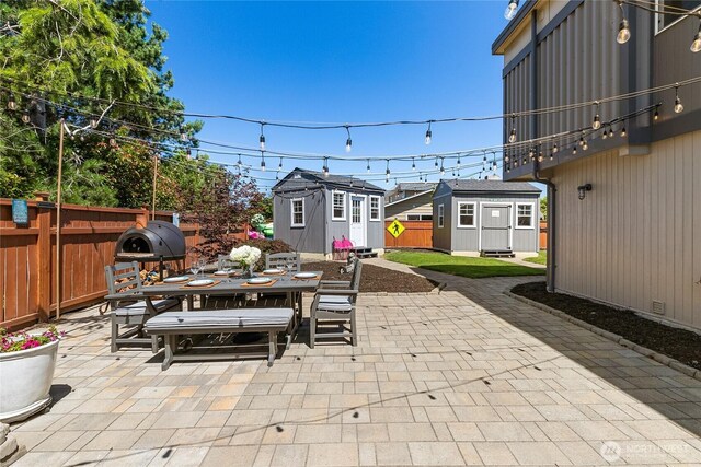 view of patio / terrace with outdoor dining area, an outdoor structure, fence, and a storage shed