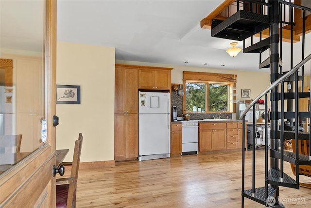 kitchen featuring light wood-style floors, white appliances, and a sink