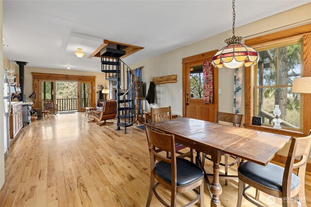dining room featuring light wood-style flooring, a healthy amount of sunlight, and stairway