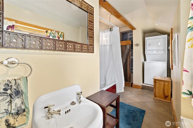 full bath featuring tile patterned floors, stacked washer / drying machine, vaulted ceiling, and curtained shower