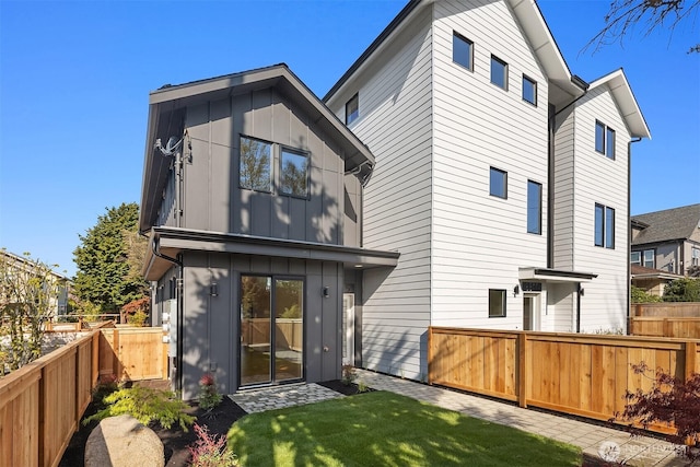 rear view of property featuring board and batten siding and a fenced backyard