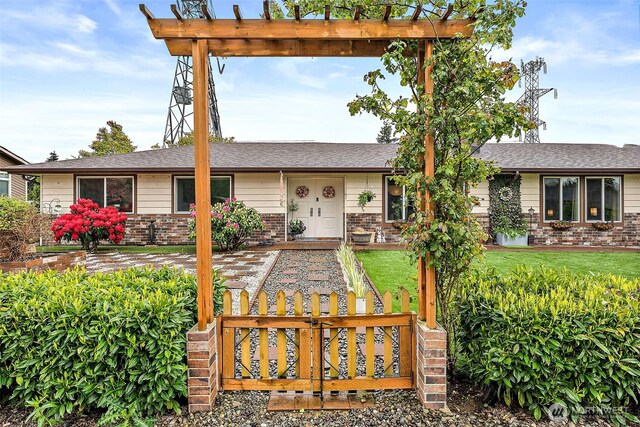 view of front facade featuring brick siding, roof with shingles, a pergola, and a front yard