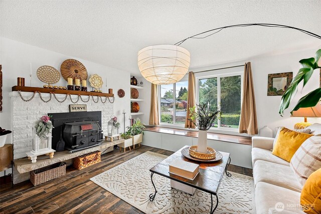 living area with a textured ceiling, wood finished floors, and a wood stove