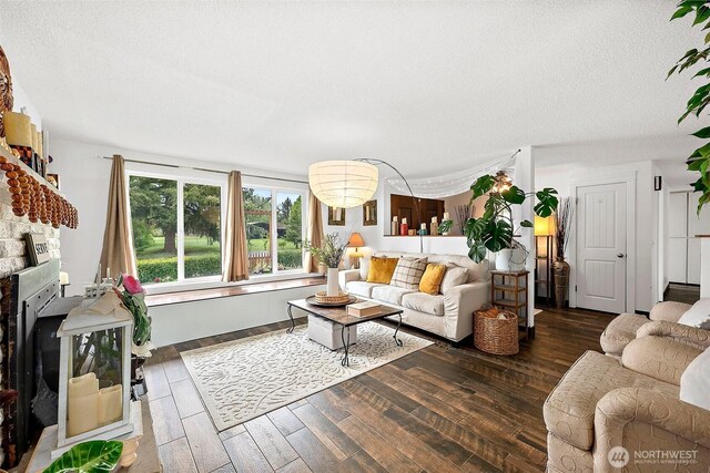 living room with a textured ceiling, wood finished floors, and a fireplace