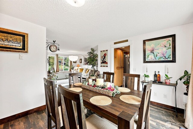 dining room featuring baseboards, dark wood-style floors, and a textured ceiling