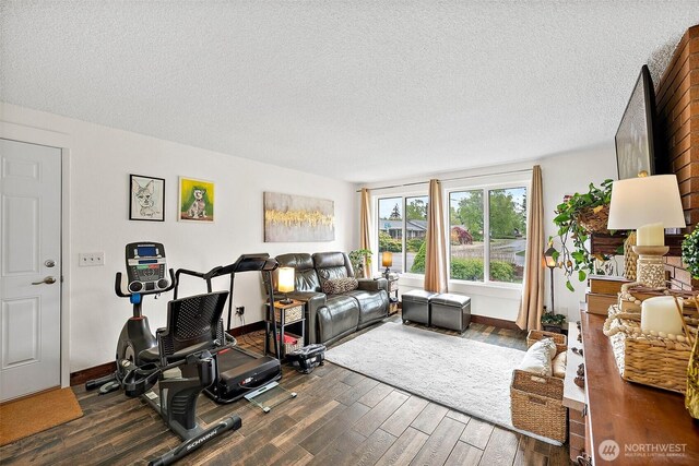 exercise area featuring a textured ceiling, dark wood-style floors, and baseboards