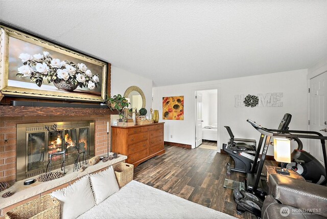 interior space with baseboards, a textured ceiling, wood finished floors, and a fireplace