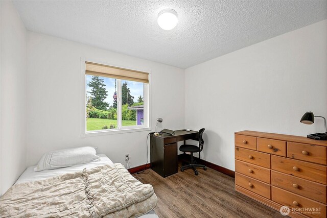 bedroom with dark wood-style flooring, a textured ceiling, and baseboards