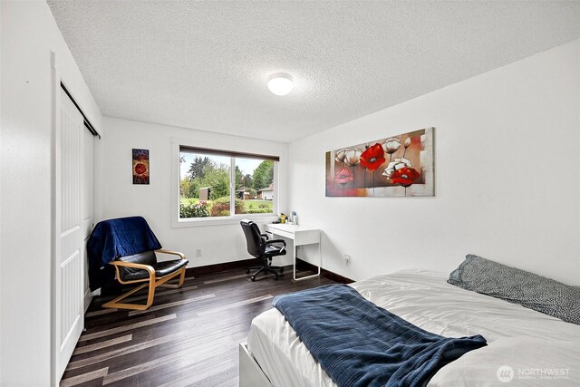 bedroom with baseboards, a textured ceiling, wood finished floors, and a closet