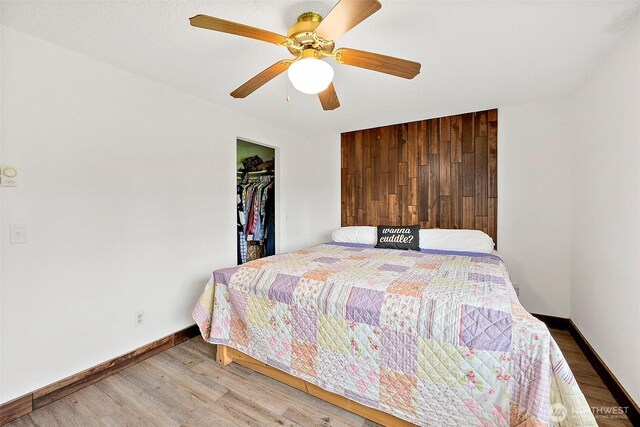 bedroom featuring a ceiling fan, baseboards, wood finished floors, and a closet