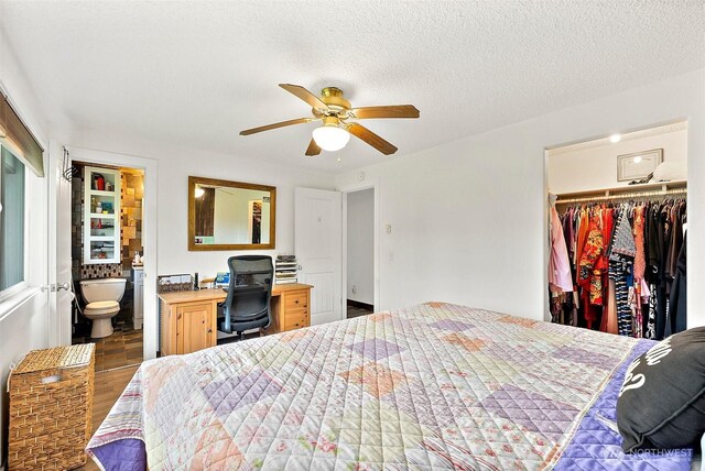 bedroom featuring ceiling fan, ensuite bath, wood finished floors, a spacious closet, and a closet