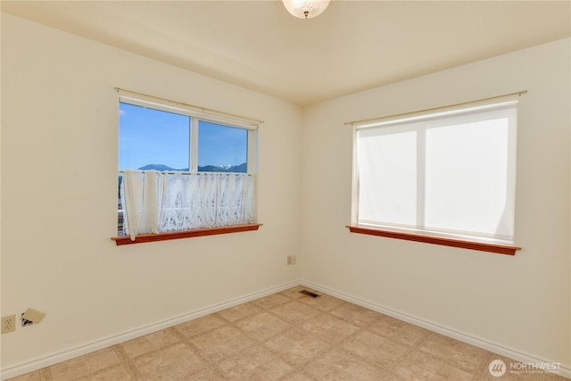 empty room featuring plenty of natural light, baseboards, and tile patterned floors