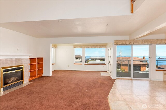 unfurnished living room with a tile fireplace, carpet flooring, and baseboards