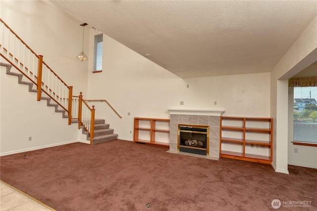 unfurnished living room with stairs, carpet floors, a textured ceiling, a fireplace, and baseboards