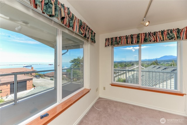 unfurnished room featuring a water view, carpet flooring, and baseboards