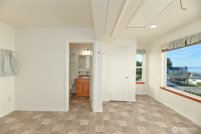 unfurnished bedroom with a sink, baseboards, recessed lighting, and connected bathroom