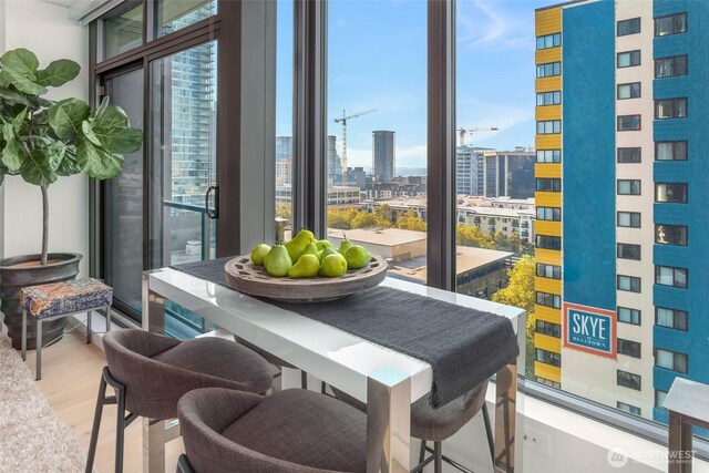 interior space featuring a view of city, wood finished floors, and a wall of windows