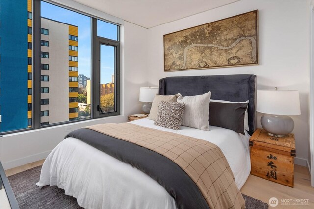 bedroom with baseboards, a view of city, and wood finished floors