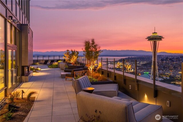 patio terrace at dusk with a mountain view, an outdoor living space, and a balcony